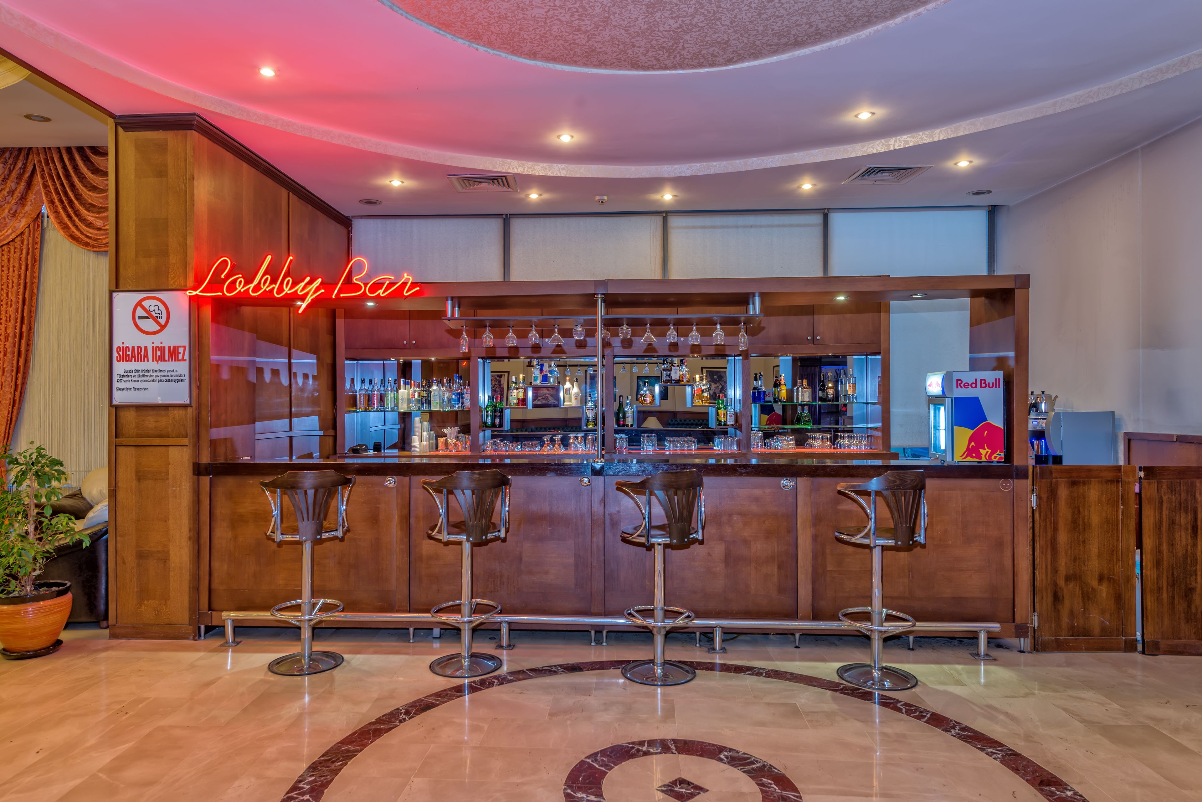 A bar area with a neon sign reading "Lobby Bar," a "Red Bull" logo, and a sign prohibiting smoking.