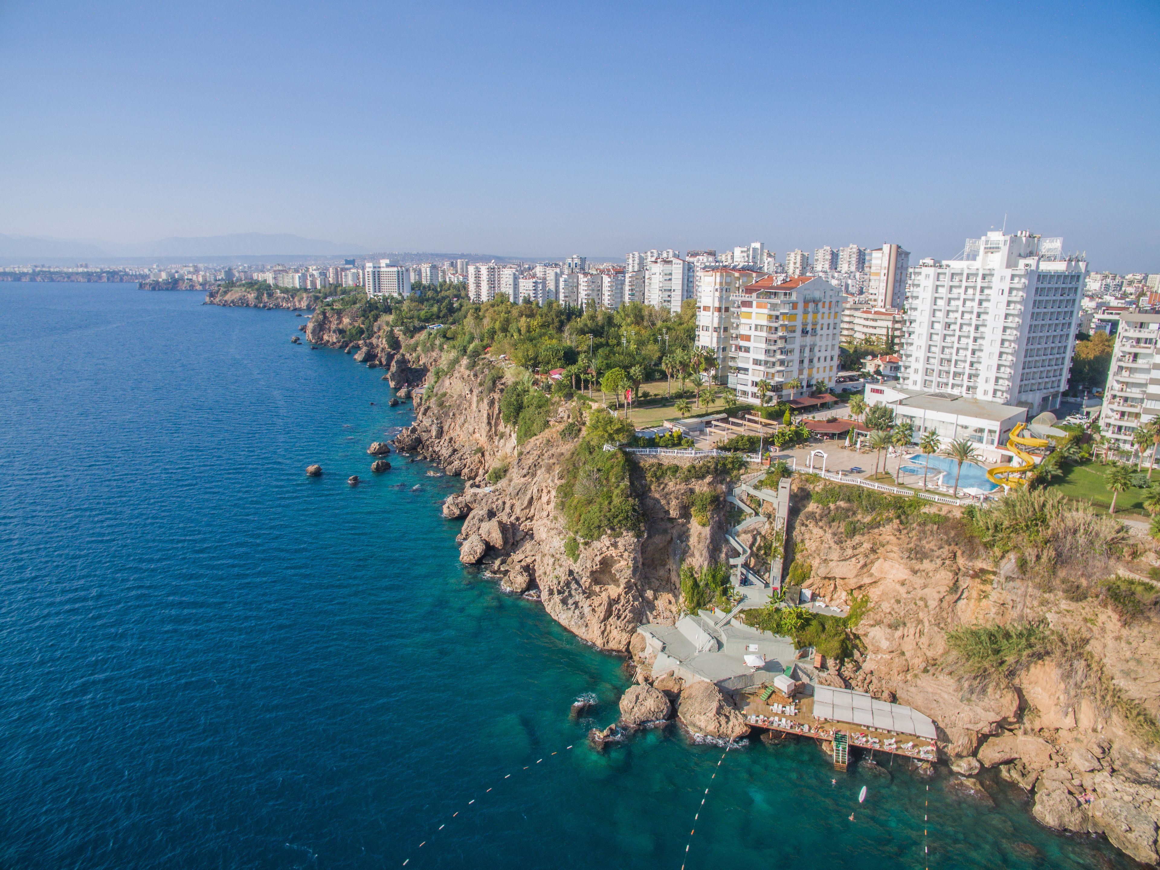 Un paisaje costero con rascacielos, una costa rocosa y un mar azul y despejado.