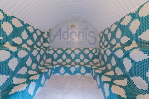 Una piscina con mosaicos y un diseño geométrico, un techo curvo y el texto