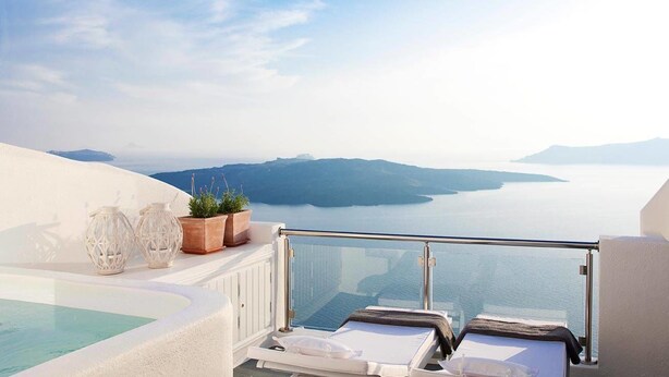 Un balcón con vistas al mar y las montañas, una piscina y dos sillas de descanso.