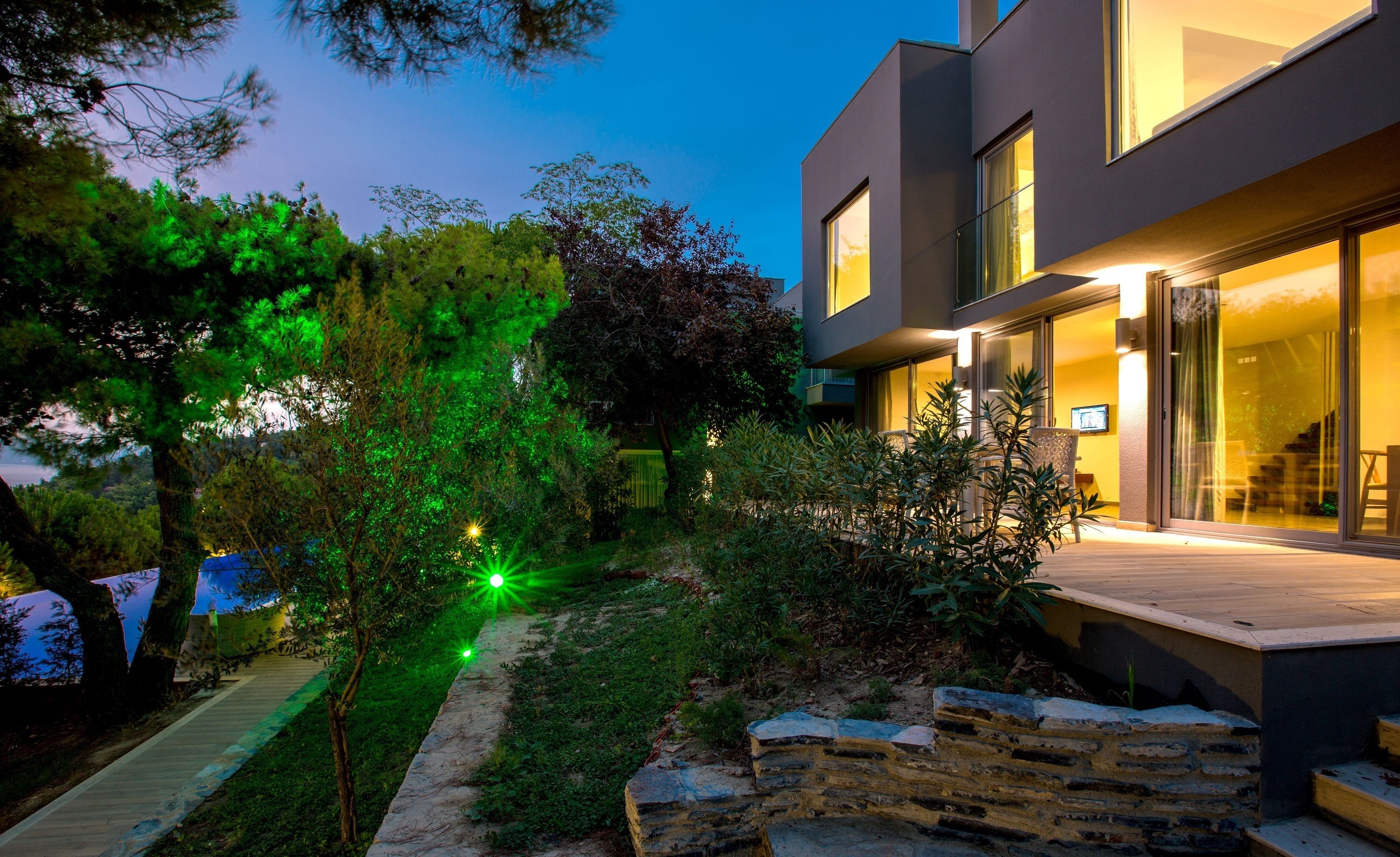 A modern house with a stone pathway leading to a wooden deck.