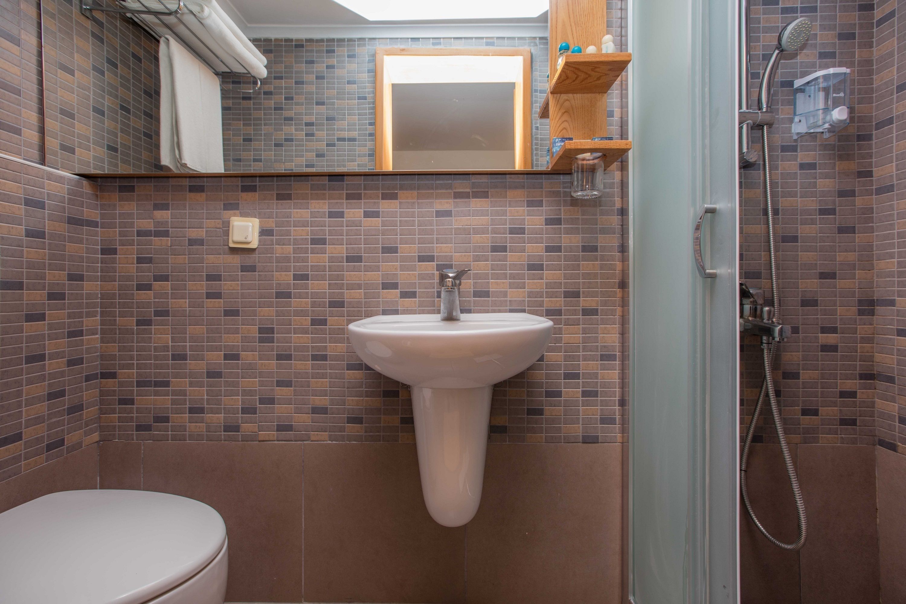 A bathroom with a white sink, a mirror, and a shower area.