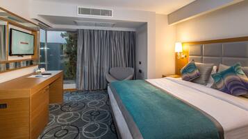A hotel room with a bed, a desk, a chair, a TV, and a window with curtains.