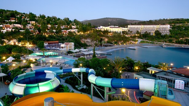 A water park with slides and pools, surrounded by buildings and a beach. - Pine Bay Holiday Resort (Kusadasi)