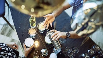 Eine Bar mit einer Person, die ein Getränk einschenkt, einer Weinflasche und verschiedenen Barutensilien auf der Theke.