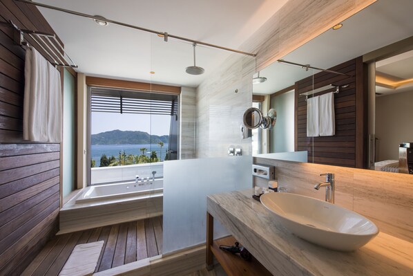 A modern bathroom with a large bathtub, a sink, and a mirror. There is a window providing a view of the sea. - TUI BLUE Grand Azur - All inclusive (Marmaris)