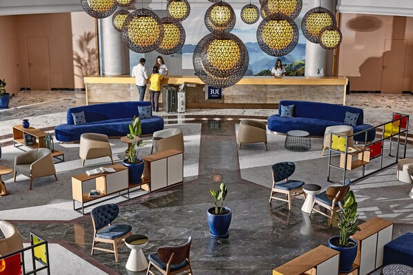 A spacious lobby with a reception desk, blue sofas, and various seating arrangements. - TUI BLUE Grand Azur - All inclusive (Marmaris)