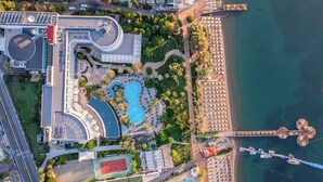 An aerial view of a resort with a large swimming pool, a marina, and a beach area.