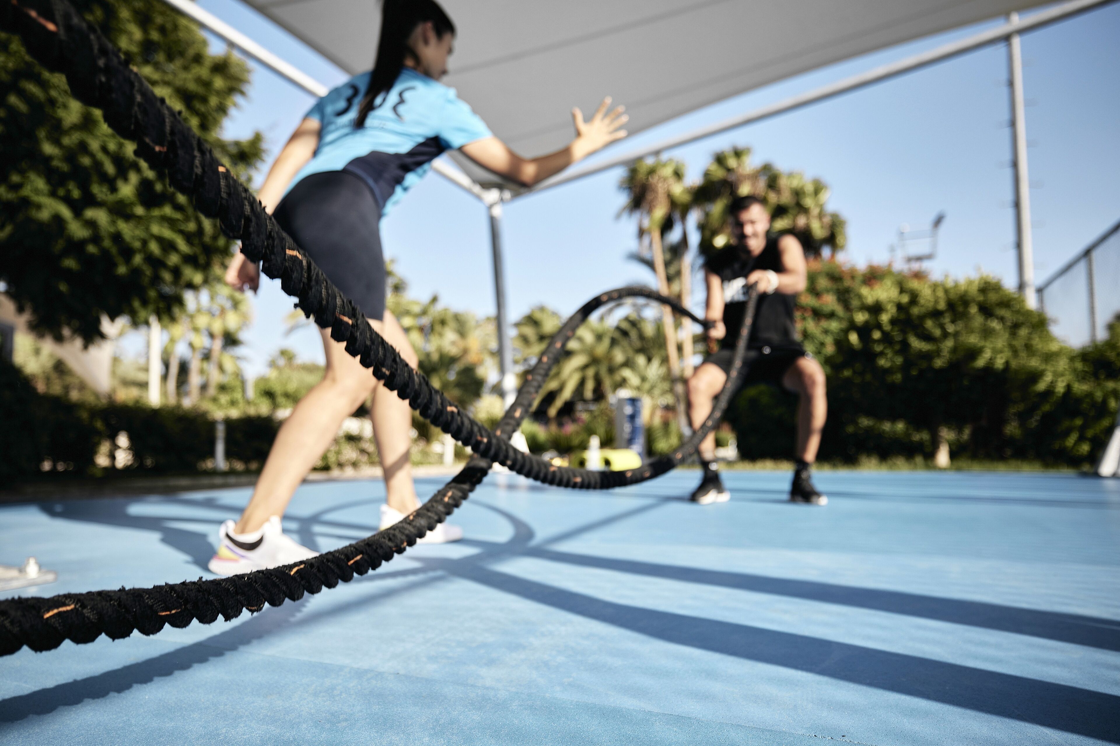 An outdoor exercise area with a blue floor and ropes for activities.