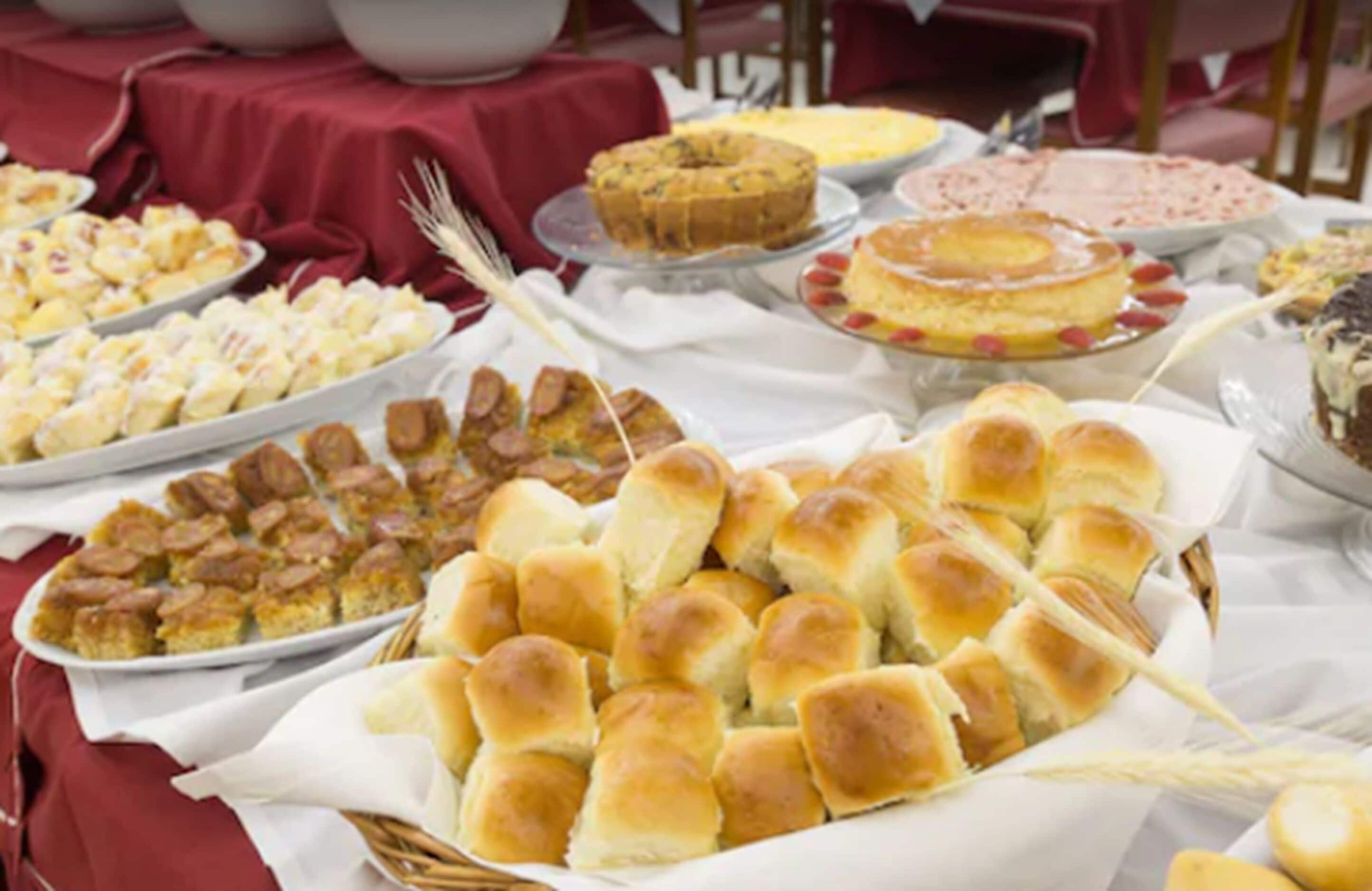 Una mesa de buffet con diversos platos, entre ellos panecillos, postres y aperitivos.
