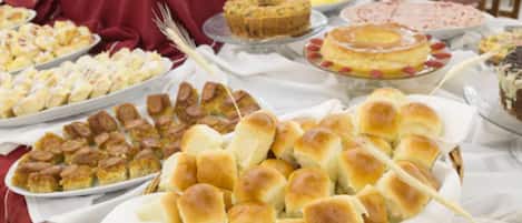 Una mesa de buffet con diversos platos, entre ellos panecillos, postres y aperitivos.