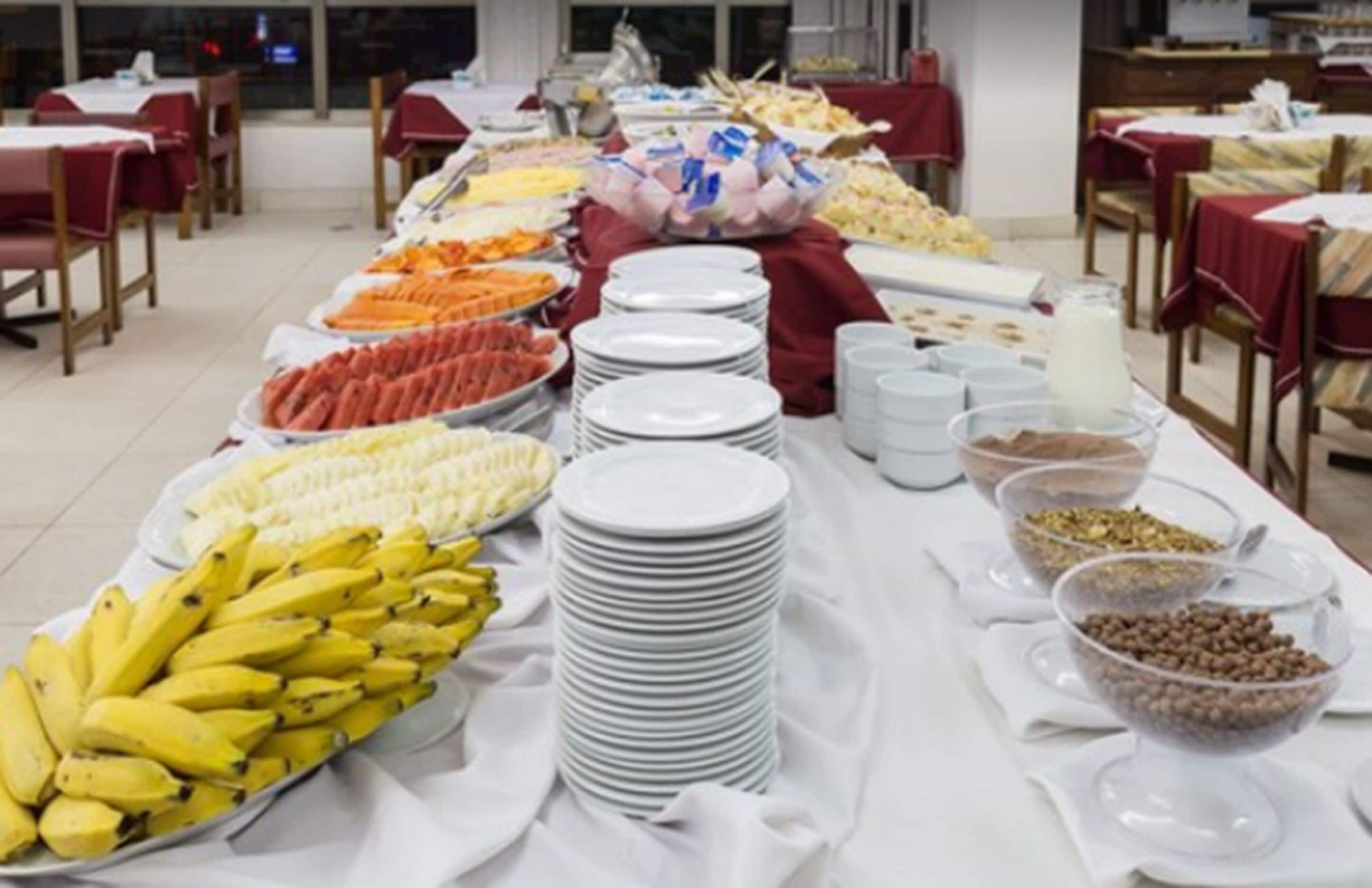 Montaje de bufé con diversos alimentos y platos blancos apilados.