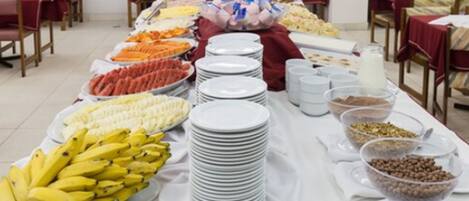 Montaje de bufé con diversos alimentos y platos blancos apilados.