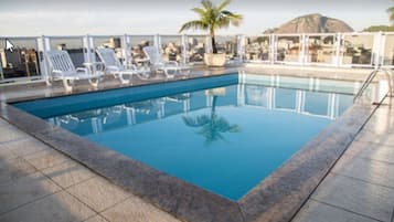 Una piscina al aire libre, sillones reclinables de piscina