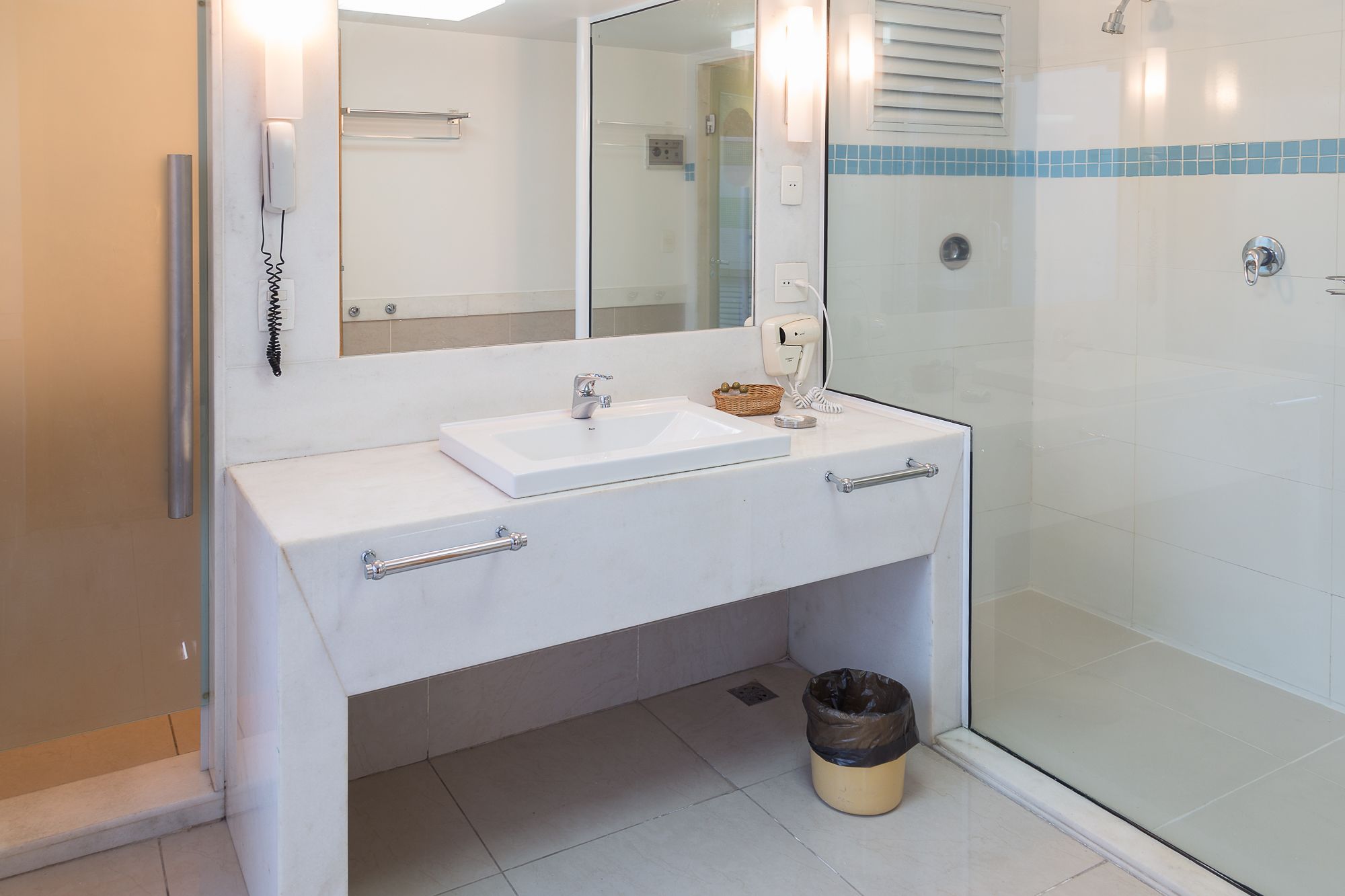 A bathroom with a white sink, a mirror, and a glass shower enclosure.