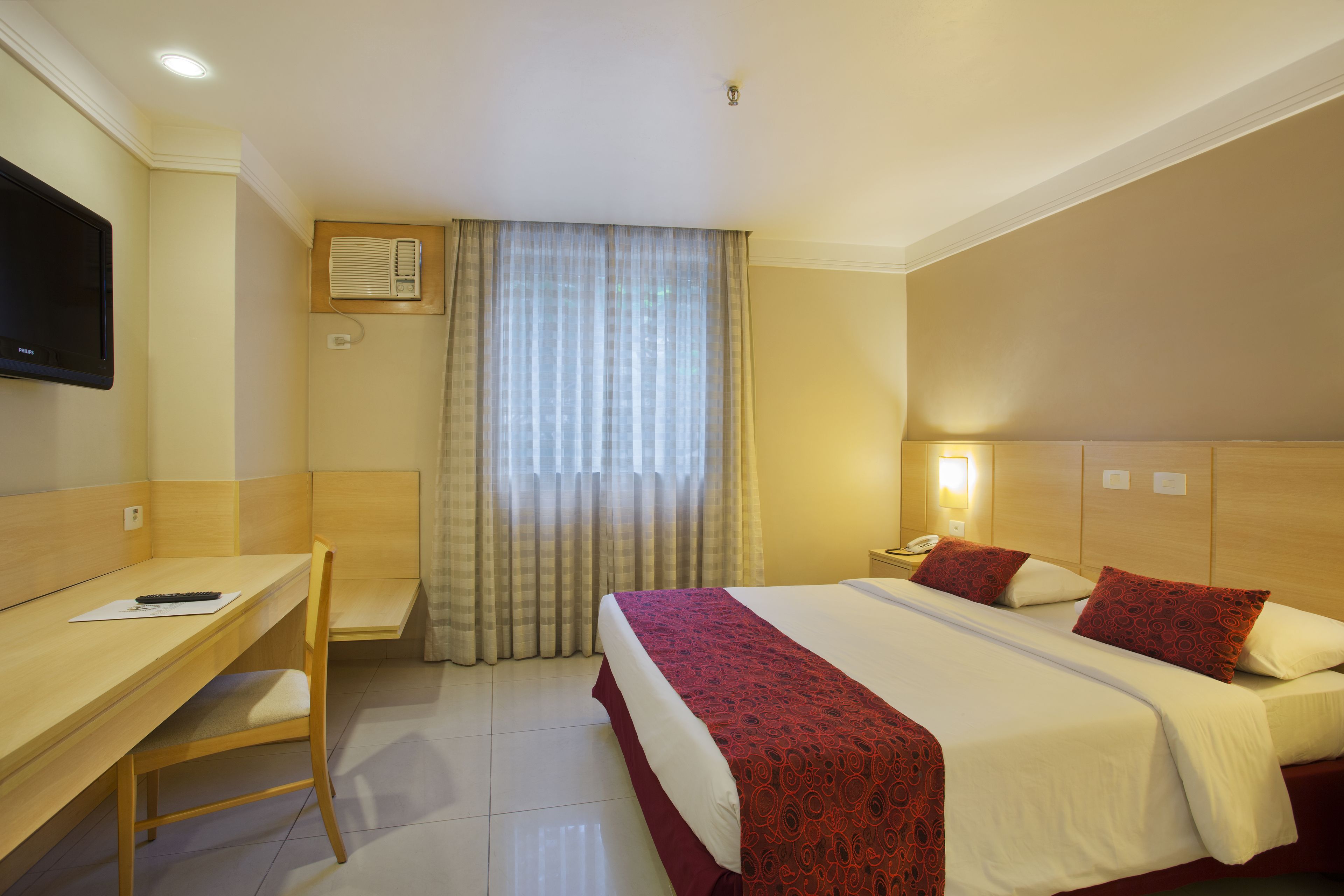 Una habitación de hotel con cama, escritorio, silla y televisor.