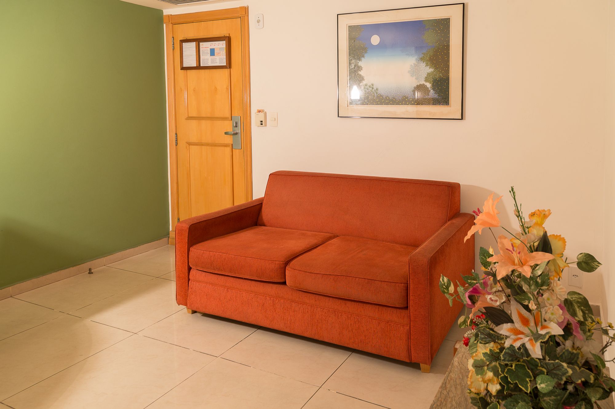 Um quarto com porta de madeira, um quadro na parede e um sofá.