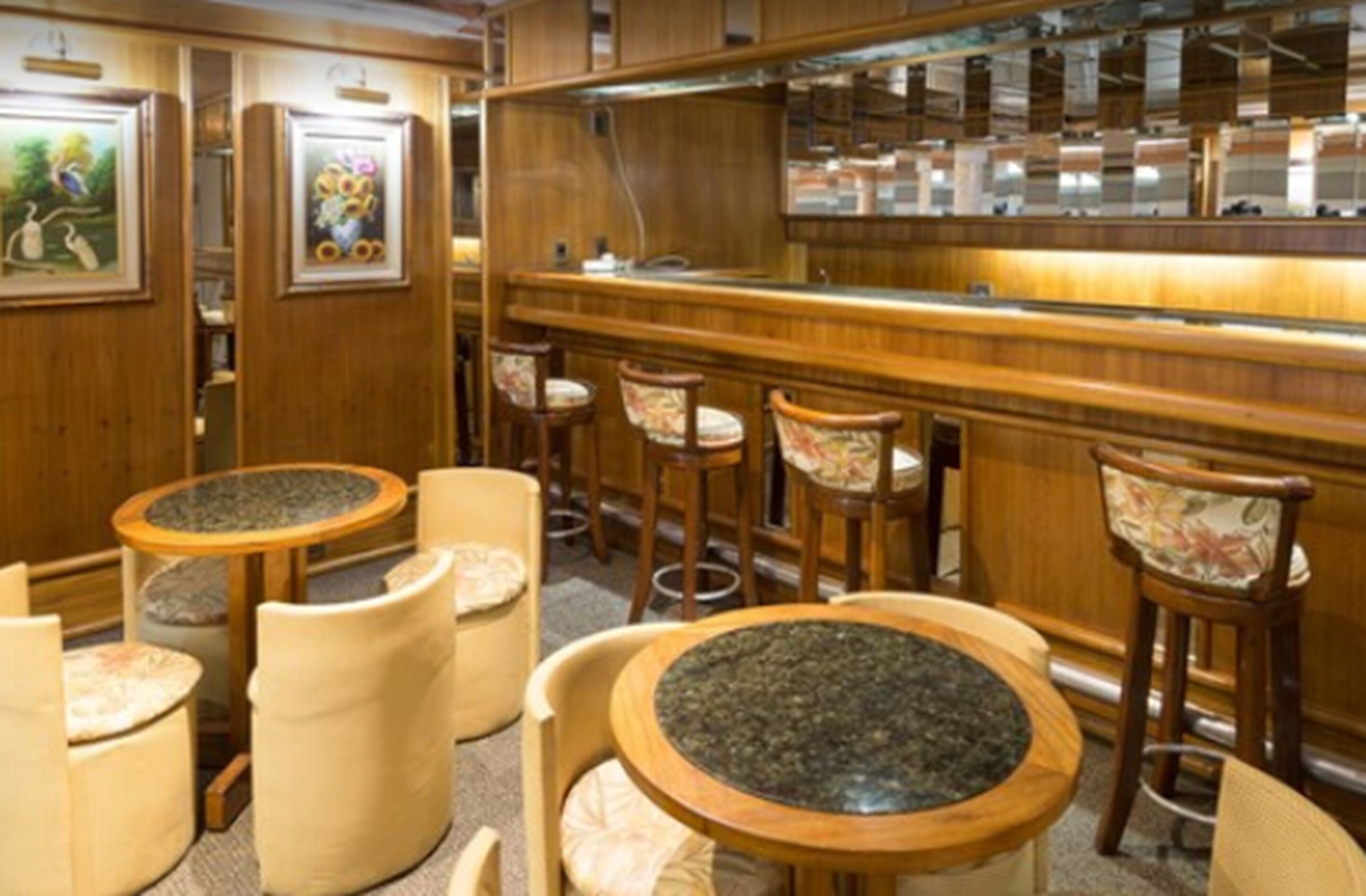 Un restaurante con decoración de madera, mesas redondas y taburetes de bar.