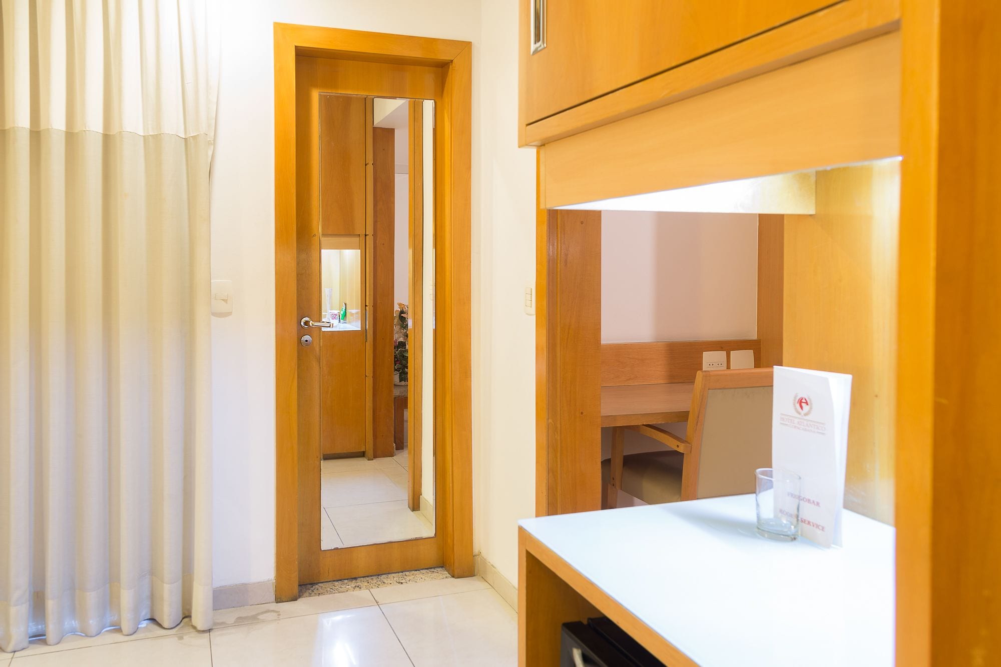 Habitación de hotel con un escritorio de madera, un espejo y una puerta que da a un baño.