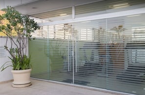 A modern building with a glass facade, a potted plant, and a metal railing. - Hotel Atlantico Copacabana (Rio de Janeiro)