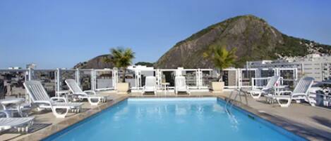 Una piscina al aire libre, sillones reclinables de piscina