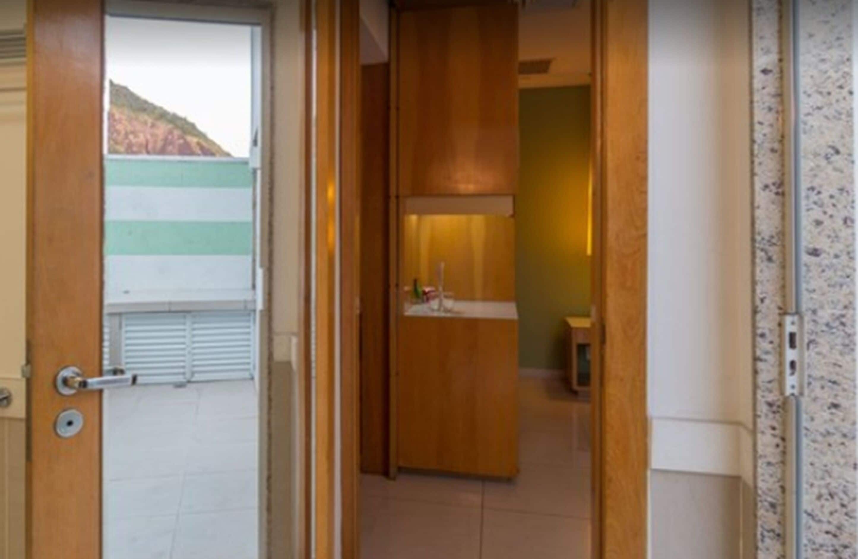 Une chambre d’hôtel avec une porte en bois, un petit lavabo et un miroir.