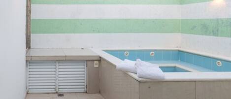 A small, enclosed swimming pool area with a tiled wall and a view of a mountain.