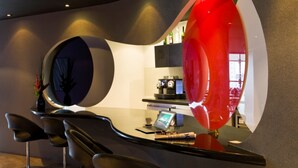 A modern bar area with a curved counter, a laptop, and a coffee machine.