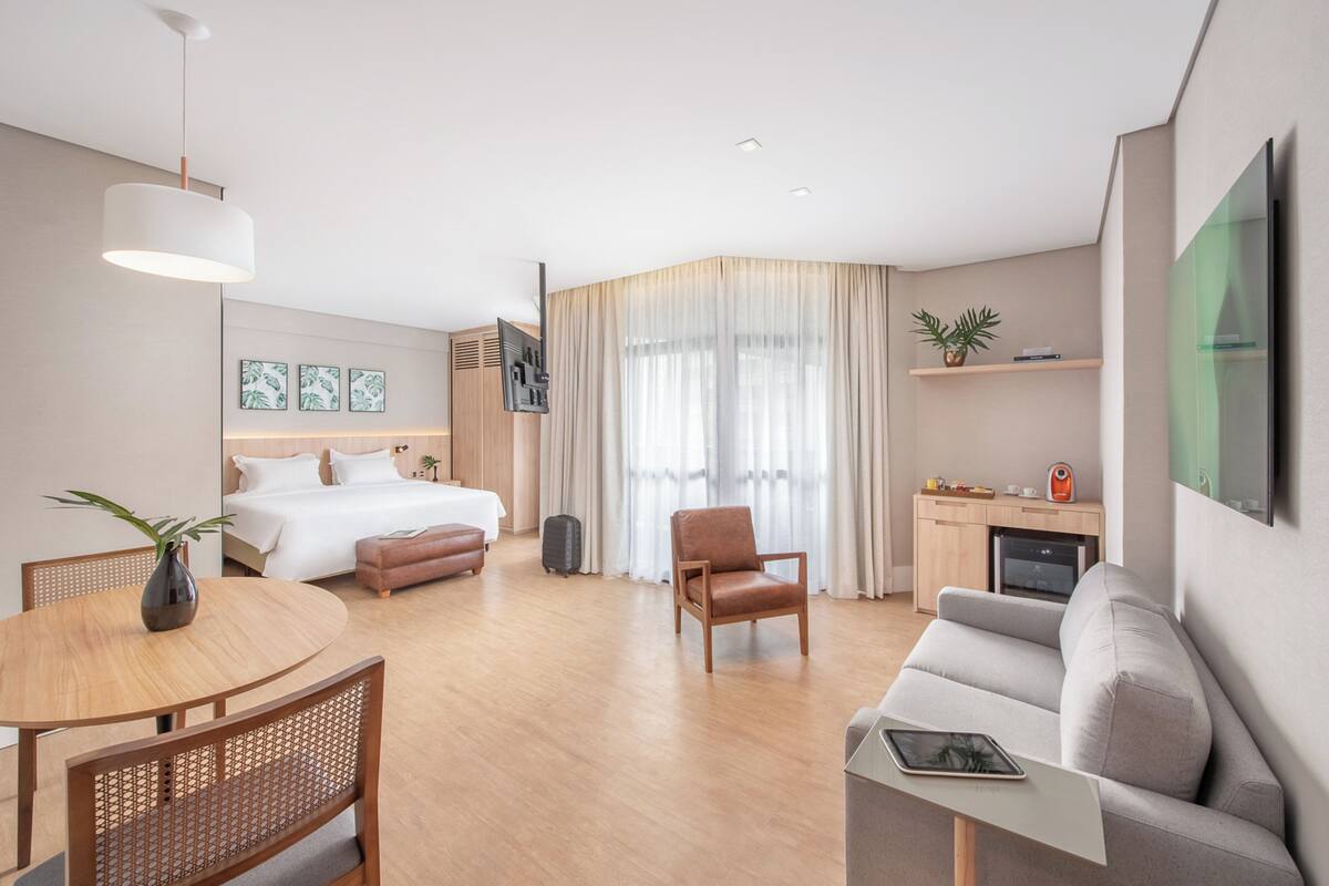 Une chambre d’hôtel moderne équipée d’un lit, d’un canapé, d’une table à manger et d’un coin cuisine.