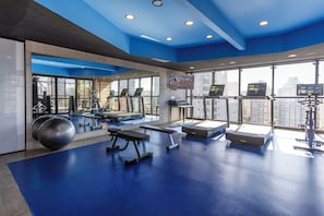 A gym with exercise equipment, large windows, and a city view.
