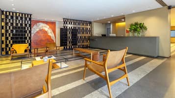 Uma área de recepção moderna, com balcão, assentos e um painel decorativo.