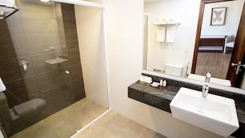 Un bagno moderno con cabina doccia in vetro, lavabo bianco e uno specchio grande.