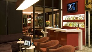 Zona de bar con televisor, barra y asientos.