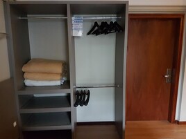 Un vestidor con estantes, una barra para colgar ropa y una puerta.