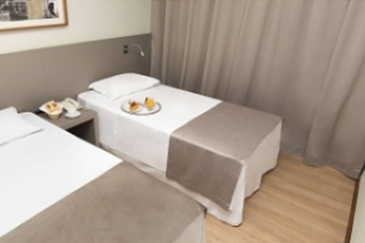 Een hotelkamer met twee bedden, een nachtkastje met een telefoon en een bord eten, en een gordijn.
