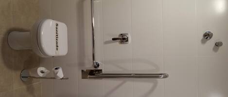 A modern bathroom with a toilet, grab bar, and toilet paper.