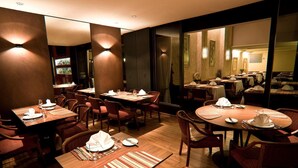 Un restaurante con varias mesas y sillas, equipado con manteles individuales y cubiertos.