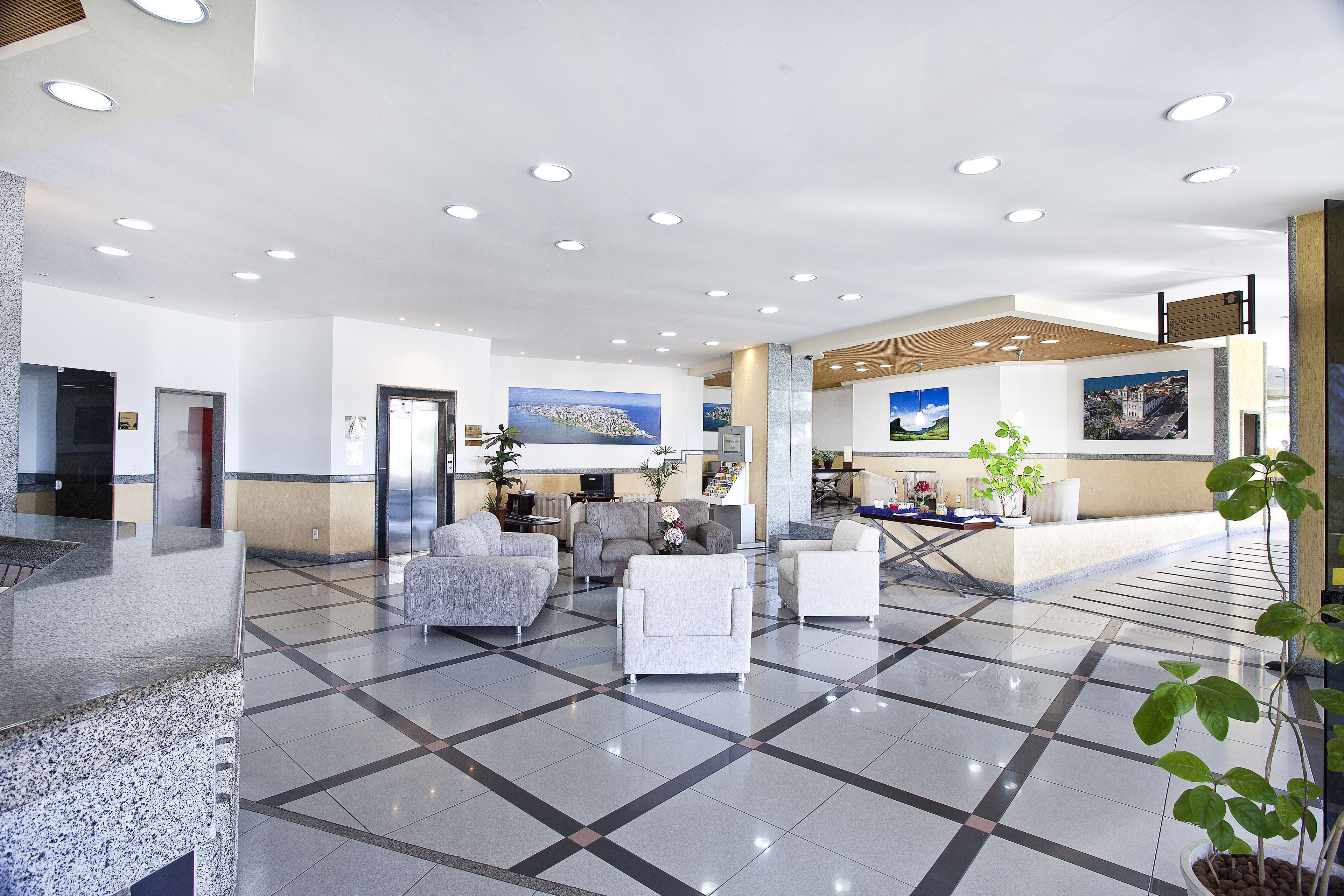 Um hall amplo com piso xadrez, área de estar e balcão de recepção.