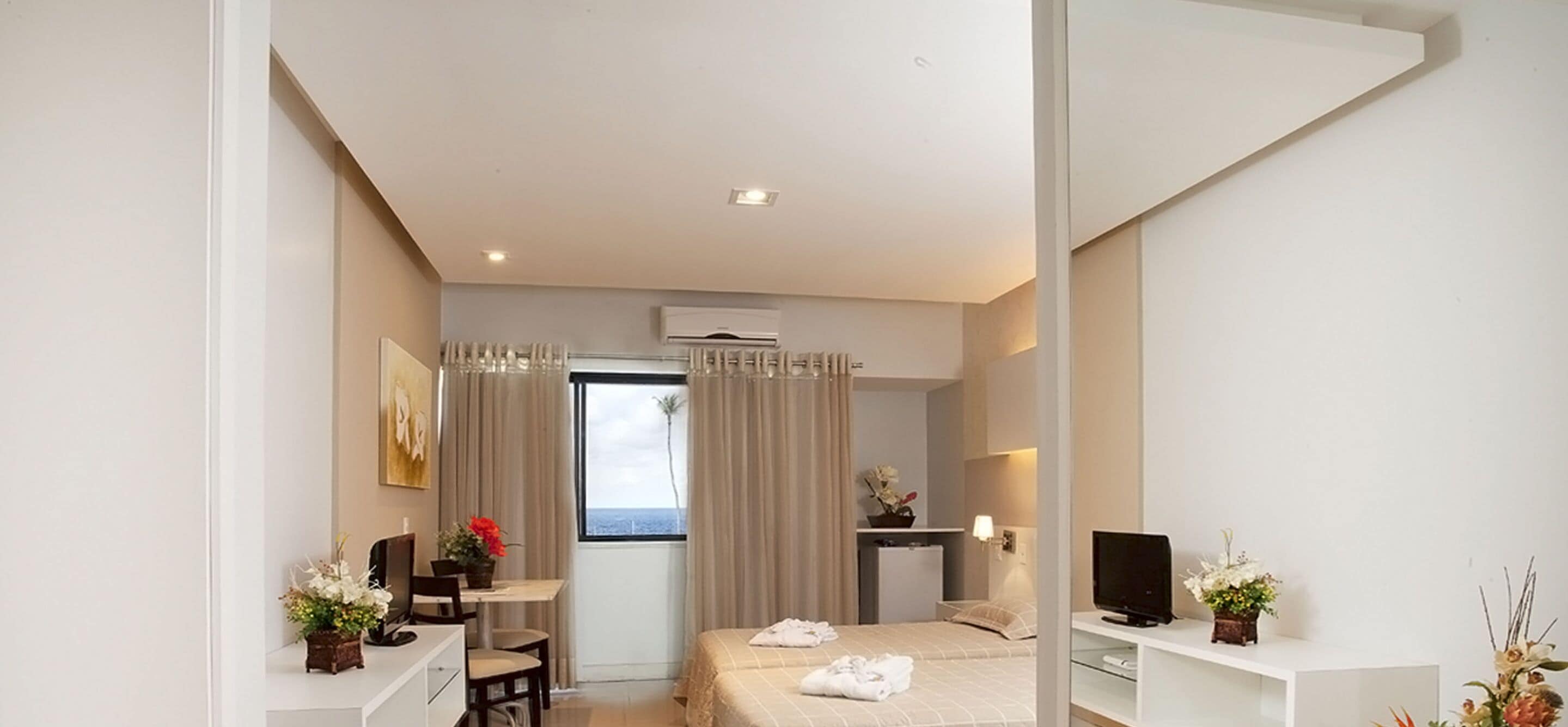 A hotel room with a bed, a desk, a TV, and a window with curtains.