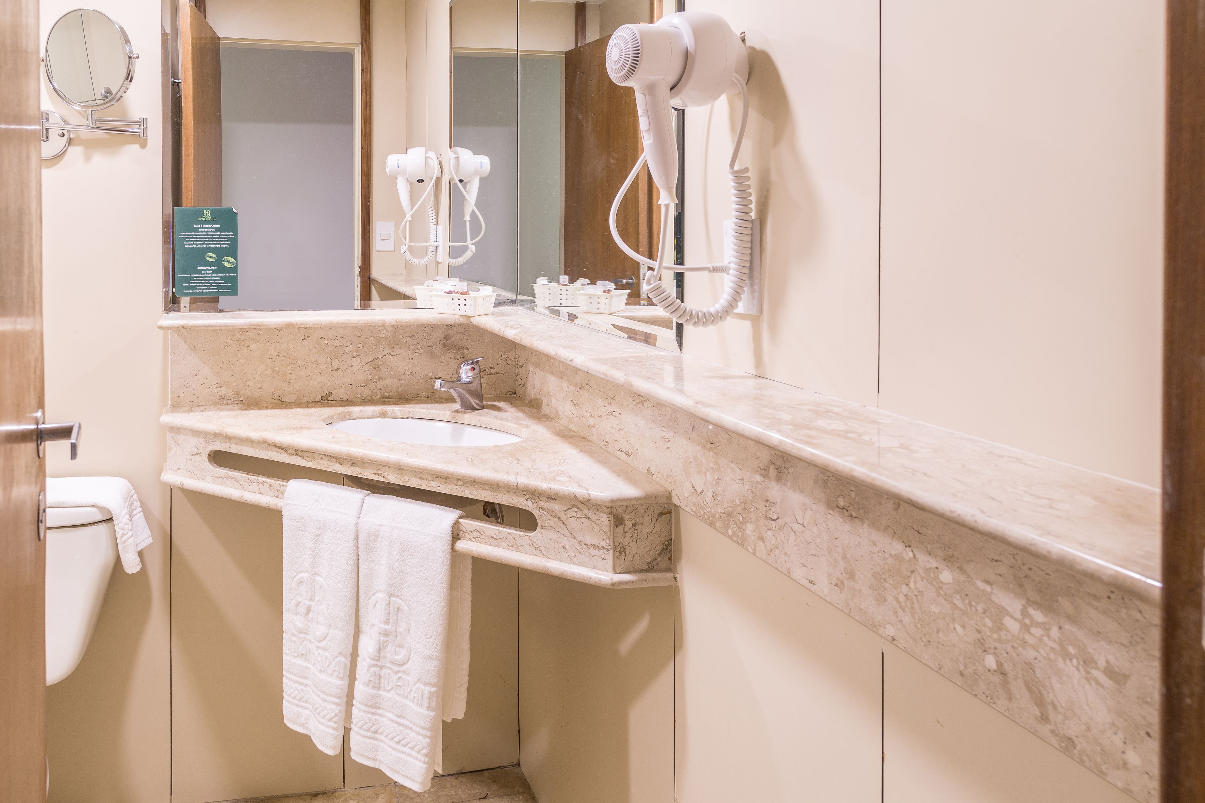 A bathroom with a sink, mirror, towel rack, and hair dryer.