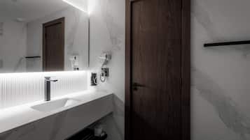 A bathroom with a marble sink, a wooden door, and a hairdryer mounted on the wall.