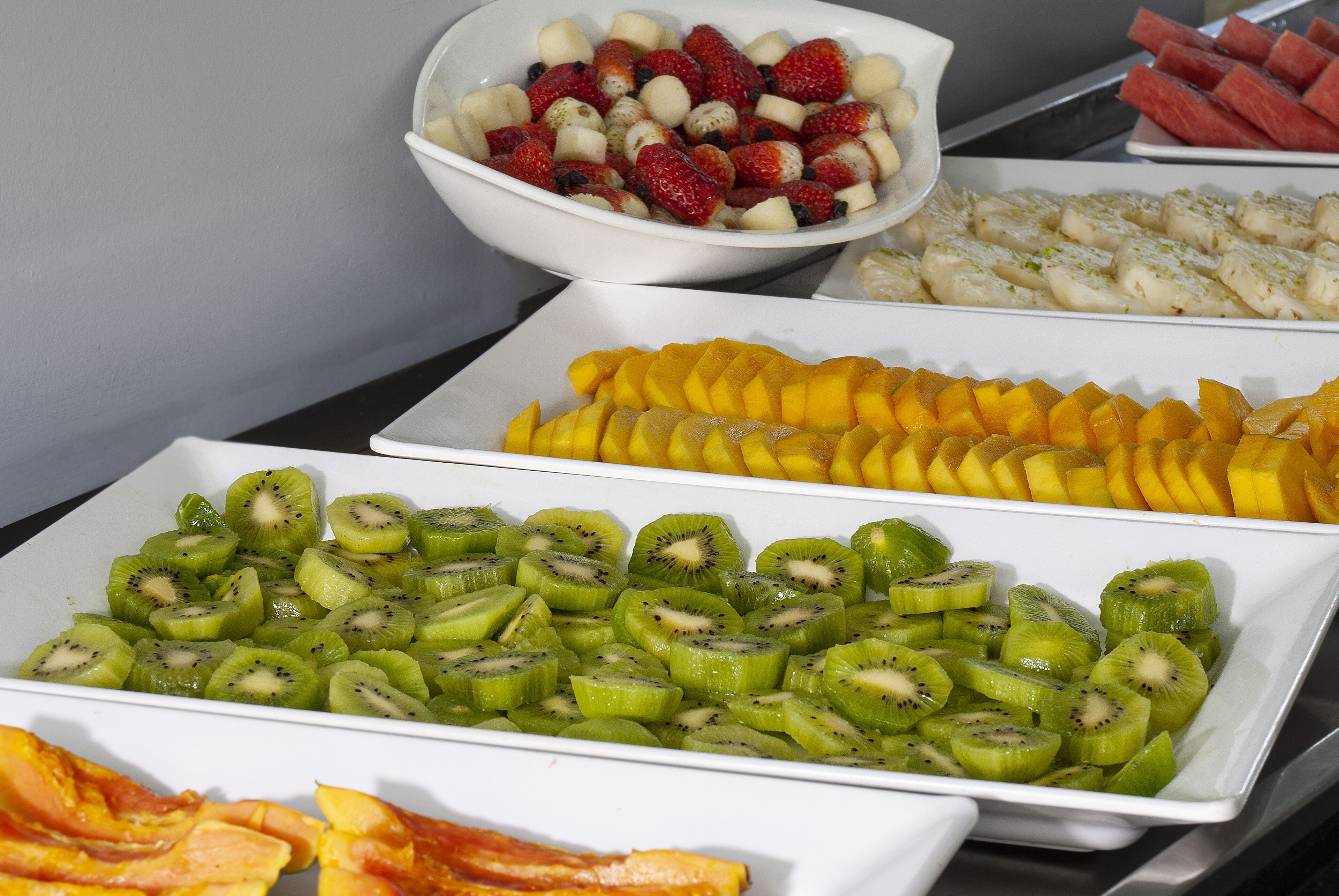 A buffet with various fruits including strawberries, kiwi, mango, and watermelon.