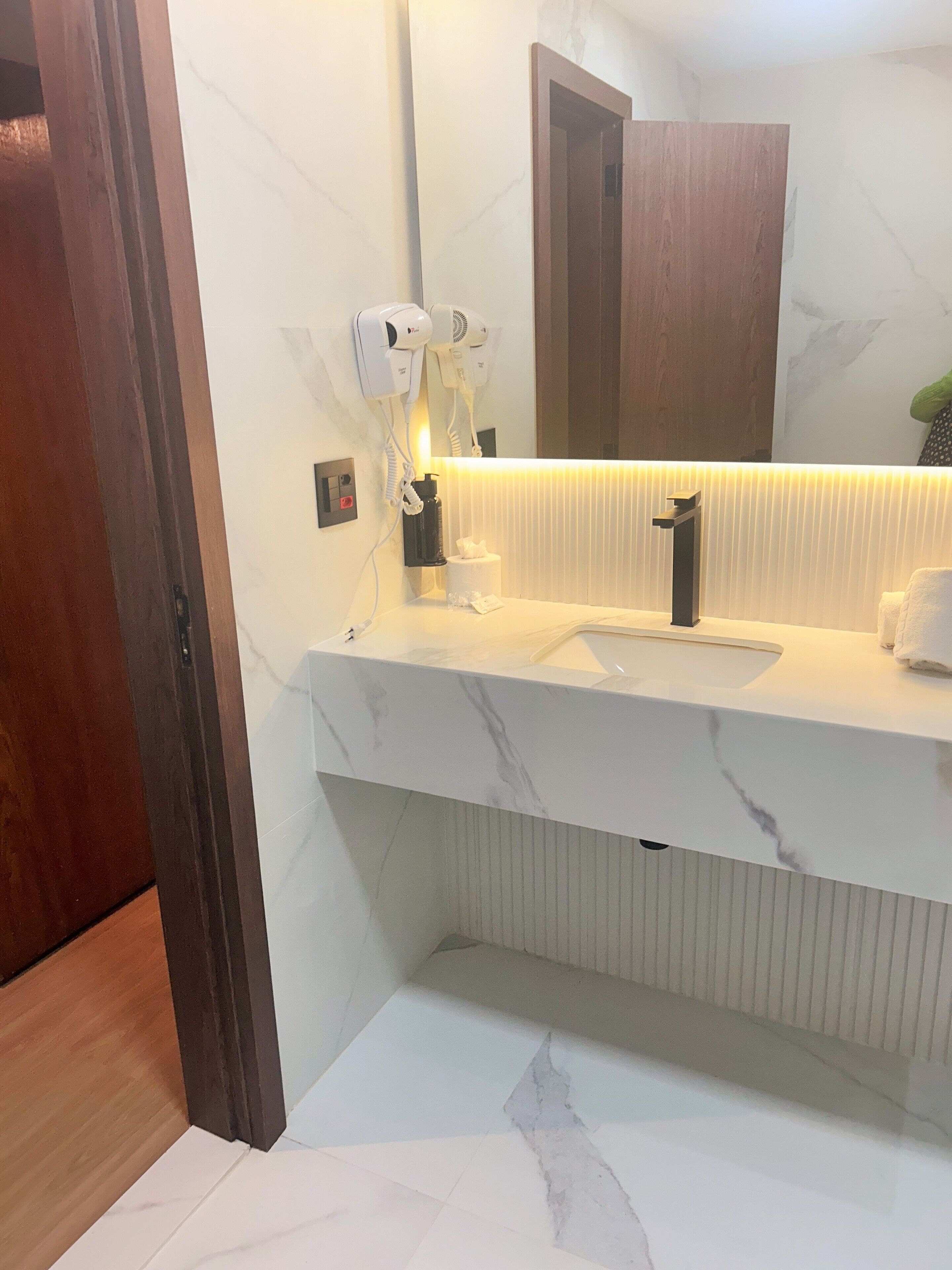Un baño moderno con encimera de mármol, un espejo grande y un secador de pelo.