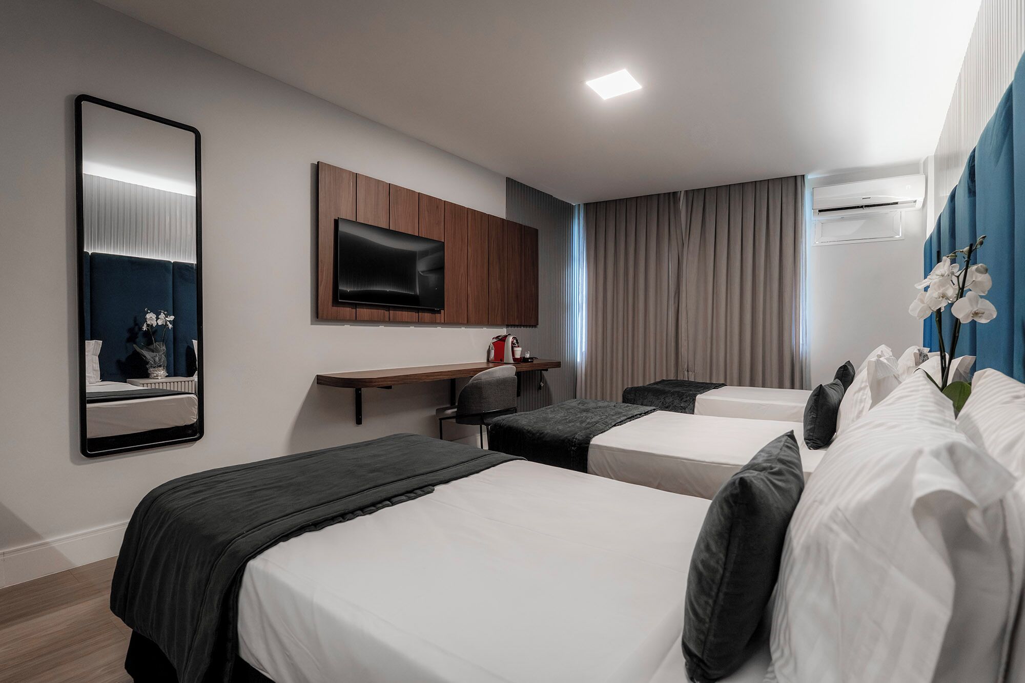Una habitación de hotel con dos camas, un escritorio, un televisor y un aire acondicionado.