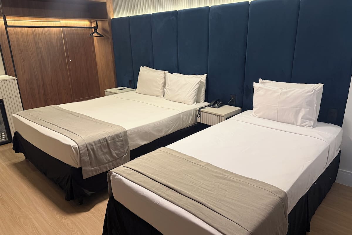 Two twin beds with white linens, a wooden wardrobe, and a blue headboard.