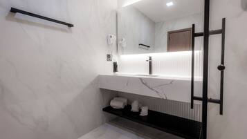 Un baño moderno con lavamanos de mármol, toallero y espejo.
