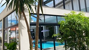 A modern building with a glass facade, a swimming pool, and surrounding greenery. - Cambirela Hotel (Florianópolis)