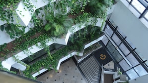 An indoor atrium with a central staircase, surrounded by lush greenery and white walls. - Cambirela Hotel (Florianópolis)