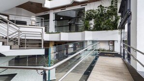 A multi-level interior with glass railings, a wooden floor, and green plants on the upper level. - Cambirela Hotel (Florianópolis)