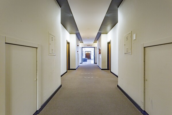 A long, narrow hallway with doors on both sides, leading to a bright room at the end. - Cambirela Hotel (Florianópolis)